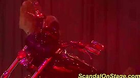 Busty milf stripping on stage with clothes ripped off in public.