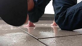 Masked figure masturbates outdoors in wet jeans on a rainy balcony.