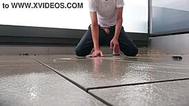 Masked figure masturbates outdoors in wet jeans on a rainy balcony.