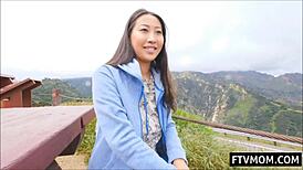 Busty Asian milf flashes big tits in daring public outdoor nude scene. Crowd watches stunned.