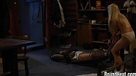 The huntress feeds her bound slave while inspecting the new european girl in leather bondage.