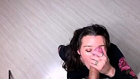 A young woman with large breasts enjoys sucking on a huge piece of candy in a playful manner.