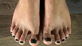 cleaning her feet with damp cloth, showing green toenails up close in sexy detail