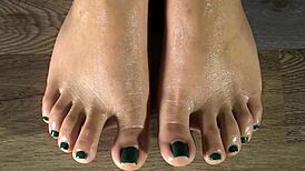 cleaning her feet with damp cloth, showing green toenails up close in sexy detail