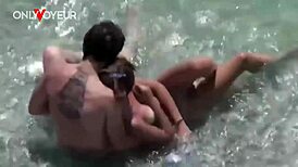 Blonde amateur couple caught in a quick fuck within ocean waves on a public beach.