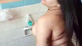 Amateur girl does striptease in bath, ripping clothes to show small tits.