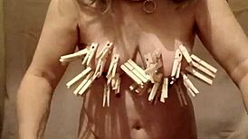 slave performs auto-session with clamps, belt, and dildo outdoors