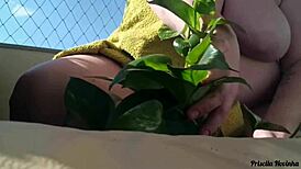 Naked Woman Waters Plants on Balcony for Curious Viewers