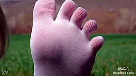 Goddess displays cute curly toes in white socks beneath jeans on spring grass field