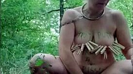 Slave humiliated in forest, bent over doggystyle with dildo while chained and slapped??
