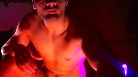 muscular bodybuilder strokes massive cock in purple orange shadows
